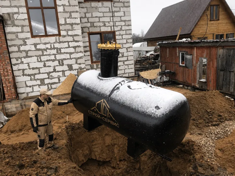Чёрный газгольдер на стропах над котлованом у строящегося дома